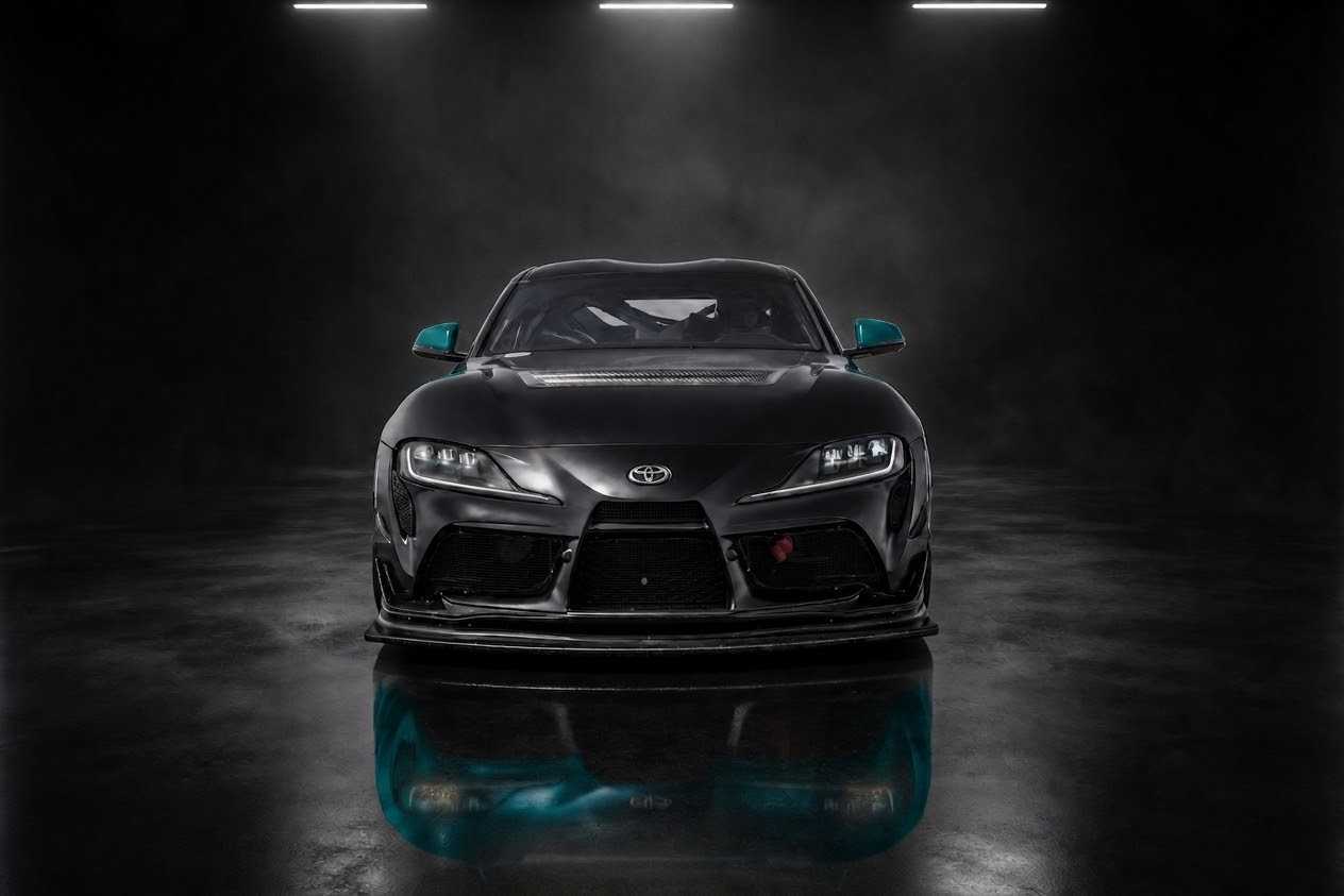 Matte black Toyota GR Supra with teal accents, lit head-on in a dark studio